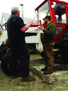 two men talking in front of a tractor